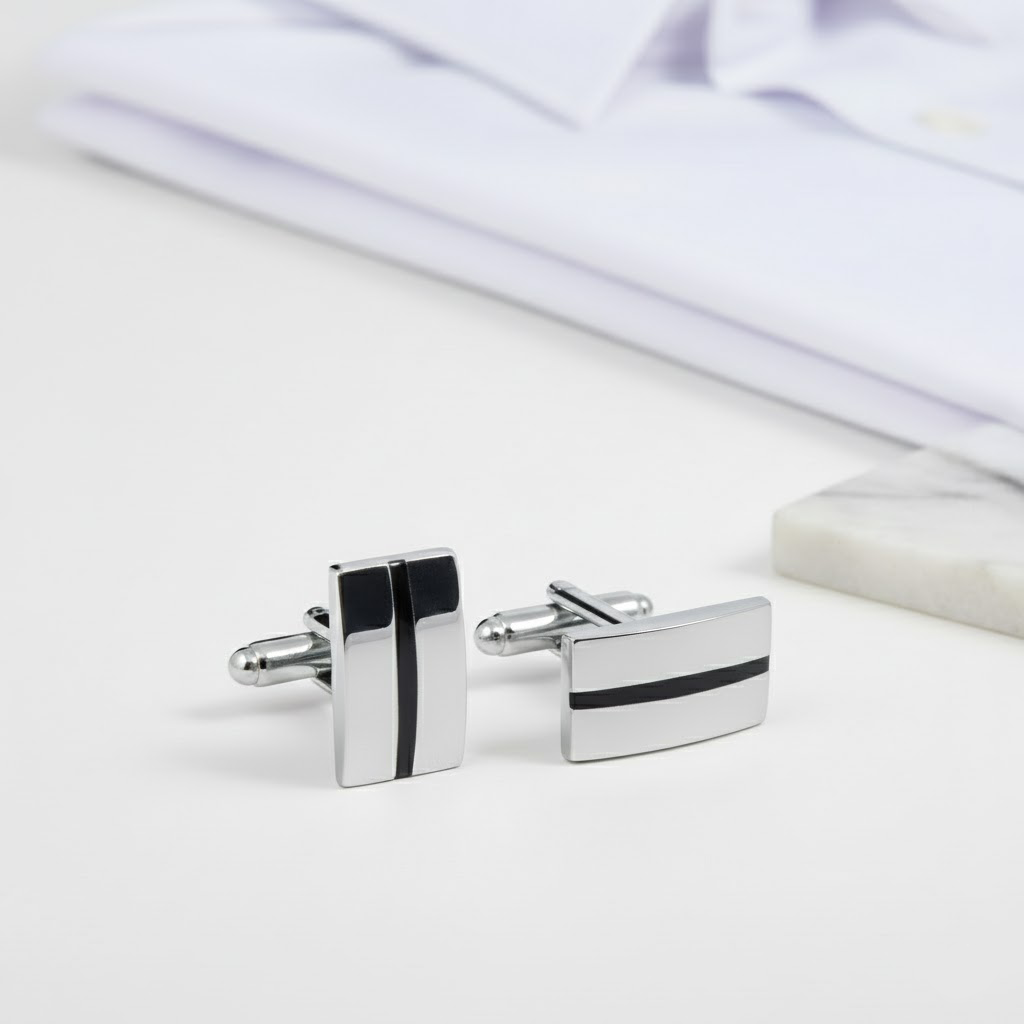 Anthony Harrison polished stainless steel cufflinks with black inlay detail on a white surface next to a folded white French cuff dress shirt.